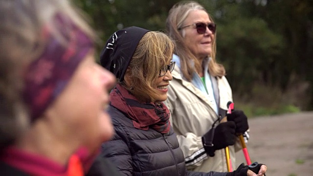 手持拍摄的女性高级朋友交谈时，手持北欧手杖在野外视频素材