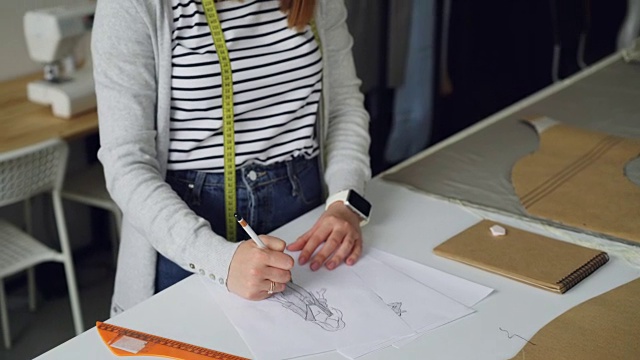 创意服装设计师倾身拍摄，专注于用铅笔在纸上画女装的素描。创造时尚服装理念。视频素材
