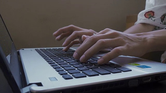 一个年轻女子在笔记本电脑键盘上打字的特写。4 k视频素材