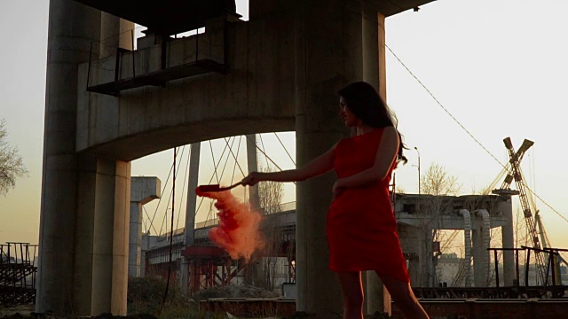 在废弃的桥下，身着红裙的美女在夕阳下跳舞视频素材