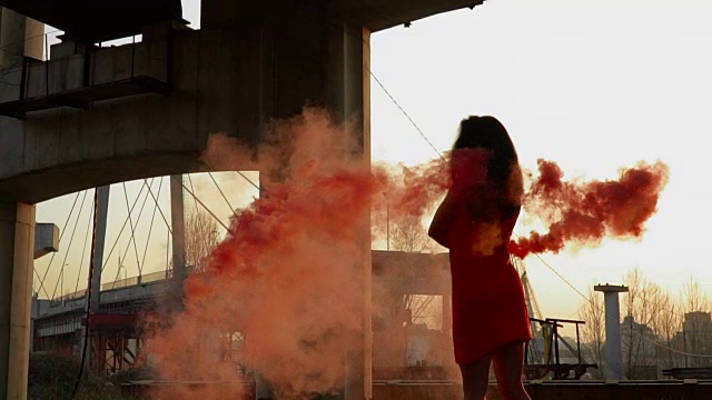 漂亮时髦的女人穿着红色的衣服与红色的烟雾在缓慢的舞蹈视频素材