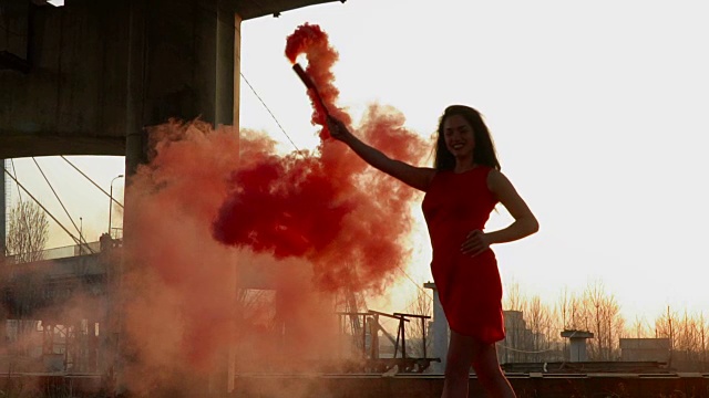 华丽的女人与红色烟雾弹在废弃的桥下跳舞视频素材