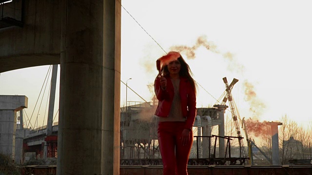 穿着红色服装的漂亮女人在废弃的桥旁与红烟跳舞视频素材
