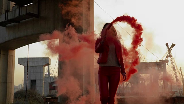 美丽的女人与红色的烟雾在废弃的地方跳舞的慢镜头视频素材