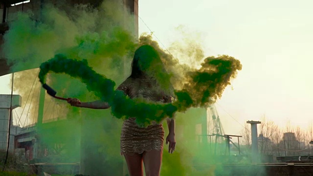 美丽的女人穿着金色的衣服和绿色的烟在废弃的桥下跳舞视频素材