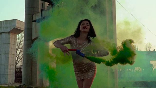 时髦的女人穿着金色的衣服和绿色的烟雾在缓慢的舞蹈视频素材
