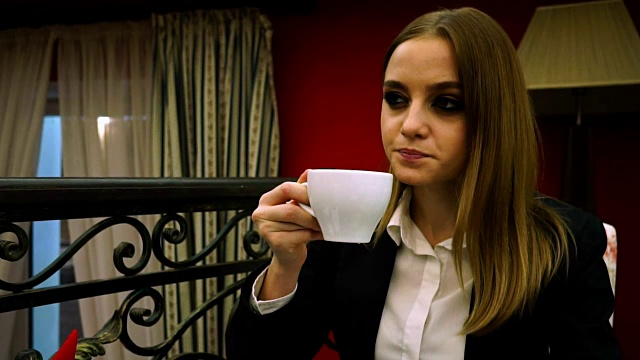 穿着商务套装的女孩若有所思地喝着茶杯里的茶视频素材