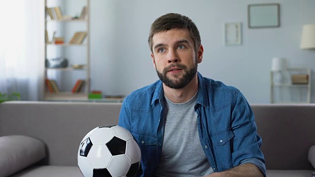 年轻人在家紧张地看电视上的足球比赛，对球队的失利感到沮丧视频素材