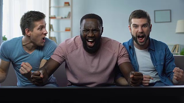 三个男人在大屏幕上观看足球比赛为最佳足球队加油视频素材
