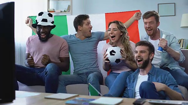 多种族的意大利球迷坐在沙发上观看比赛，庆祝进球视频下载