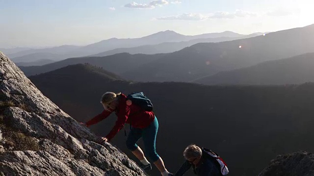 徒步旅行的夫妇攀登岩石脊山顶视频素材