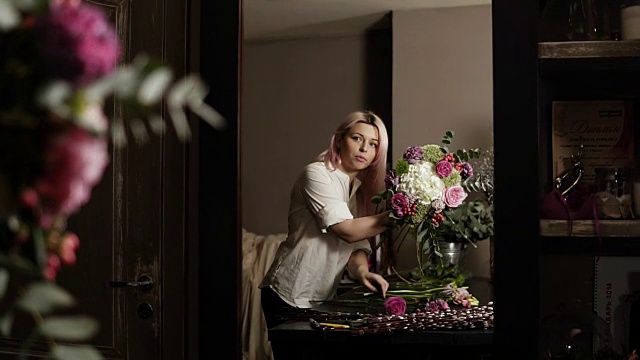 一个漂亮的花商女孩看着镜子里的倒影纠正并装满了一束花视频下载