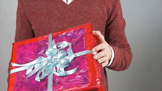 一个年轻人和一份礼物。一个有吸引力的男人拿着一个盒子。视频下载