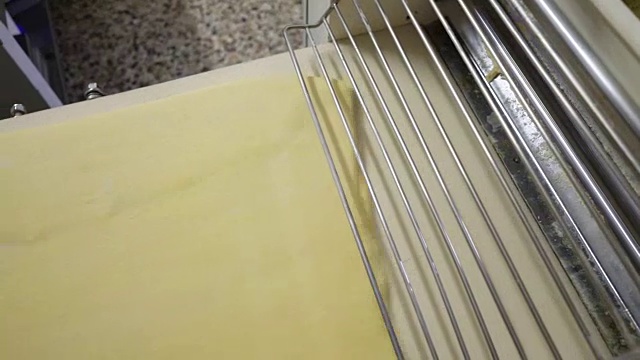 传统的意大利面包店。一位女面包师用一种特殊的机器擀面团视频素材