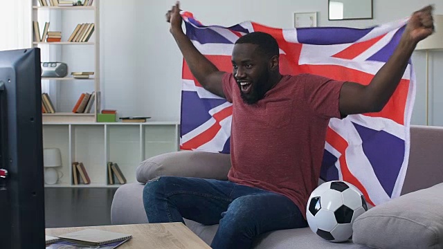 英国球迷挥舞旗帜为国家队加油，在家看比赛视频素材