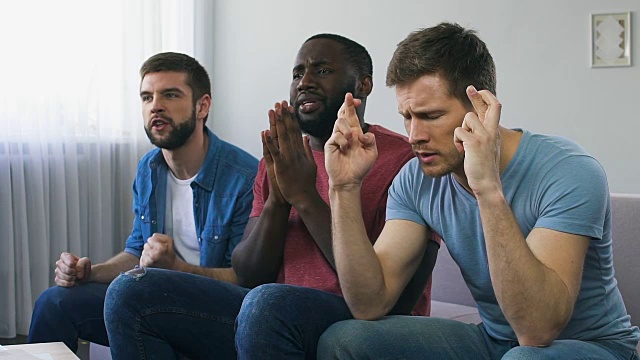 男人看体育比赛，祈祷团队获胜，迷信手势，希望视频素材