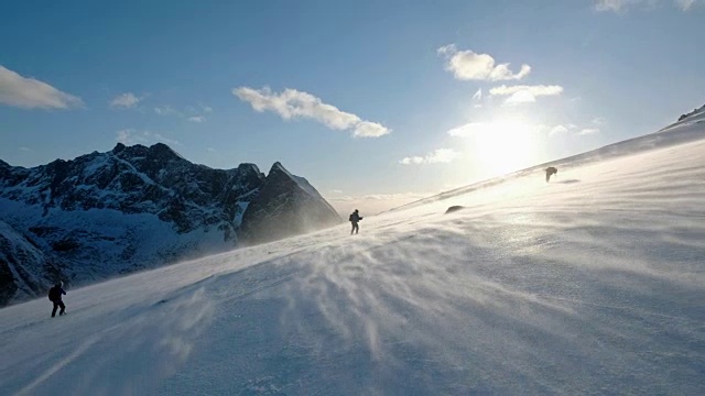 在有暴风雪的山坡上徒步旅行的登山队视频素材