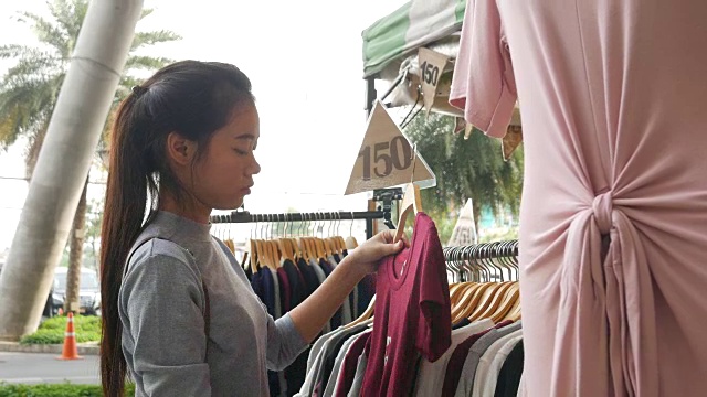 年轻的亚洲妇女在街头市场购物视频素材