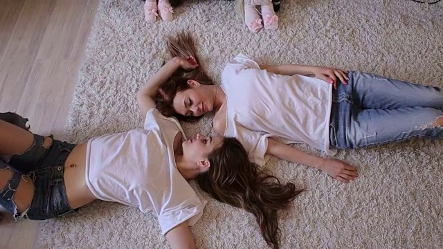 两姐妹躺在地毯上，挥舞着双手。视频下载