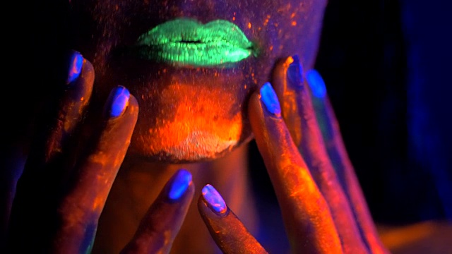 时尚性感的迪斯科女孩跳舞在霓虹灯。荧光化妆在紫外线下发光。神秘女子与绿色嘴唇UV油漆。节目和音乐概念视频下载