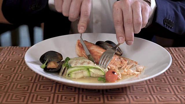 美食餐厅里的海鲜和蔬菜菜肴的特写。穿西装的人在吃盘子。视频下载