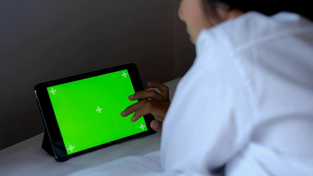 亚洲女性躺在床上使用绿色屏幕的智能手机或平板电脑视频素材