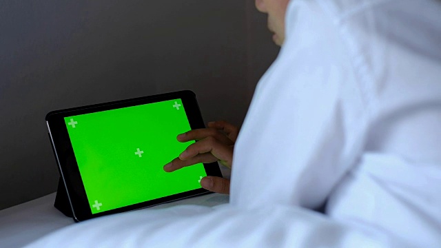 亚洲女性躺在床上使用绿色屏幕的智能手机或平板电脑视频素材