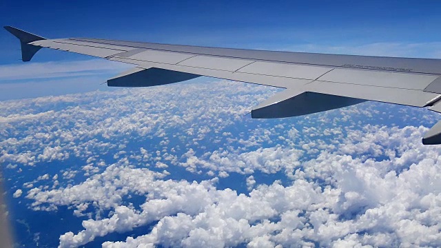 旅行视频从飞机窗口透过机翼和发动机观看在交通或旅行概念中飞行时穿过云层和蓝天。视频素材