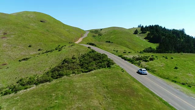 鸟瞰图的汽车驾驶下的乡村道路通过农村起伏的山视频素材