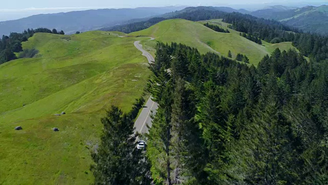 鸟瞰图的汽车驾驶下的乡村道路通过农村起伏的山视频素材