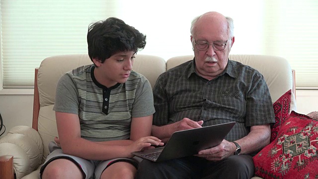 男孩和爷爷在沙发上玩电脑视频素材