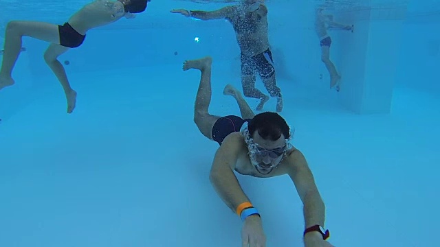 游泳池里的人群被水下摄像机拍摄到，一个人正朝它移动视频下载