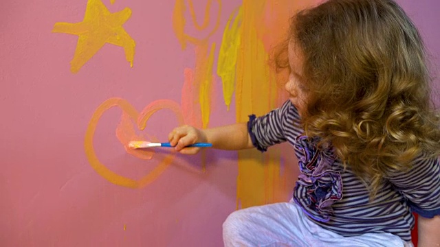小女孩在墙上画星星和心视频下载
