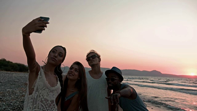 年轻的多民族潮人朋友在海滩上自拍日落视频素材