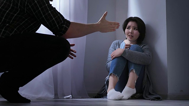 悲伤的亚洲女人坐在地板上，愤怒的丈夫威胁，家庭冲突，暴力50fps视频下载