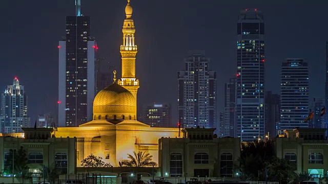 现代迪拜城市的天际线与拉希德Al Hadeeth清真寺在夜晚与水面上发光的摩天大楼的时间推移视频下载