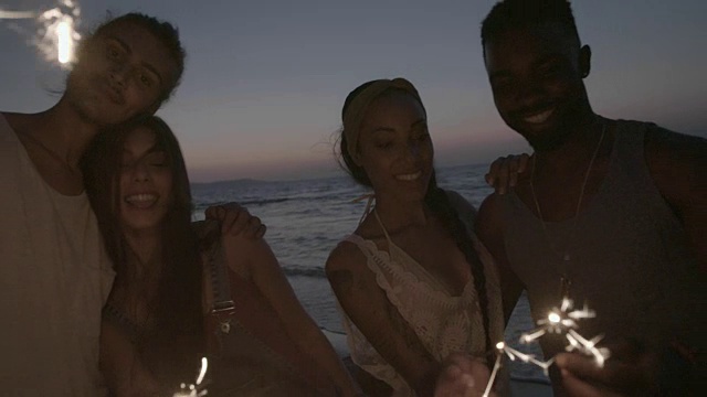 多民族的情侣晚上在海滩上用烟花庆祝视频素材