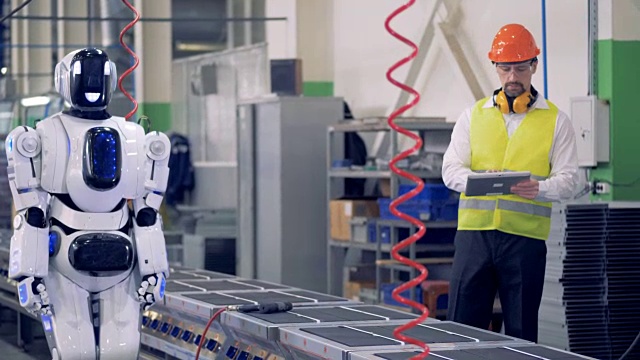 工程师控制机器人在工厂的传送带上工作。4 k。视频素材