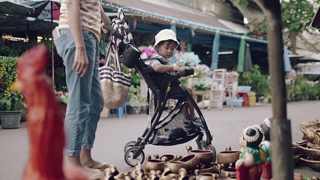 亚洲妇女和男婴在跳蚤市场买装饰品。视频素材