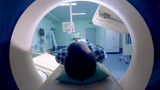 一个男人从断层扫描仪里出来。层析x射线摄影机。病人接受磁共振医学检查。视频素材