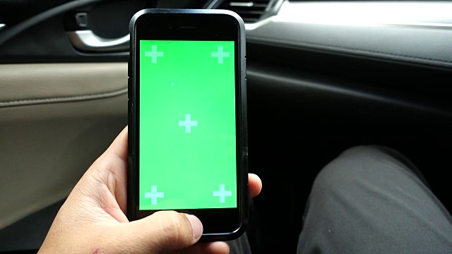 特写:亚洲男性手持和使用智能手机绿色屏幕在车里。视频素材