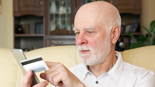 老人在家用智能手机刷卡网购。老年人使用的技术视频下载