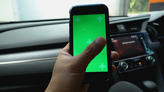 特写:亚洲男性手持和使用智能手机绿色屏幕在车里。视频素材