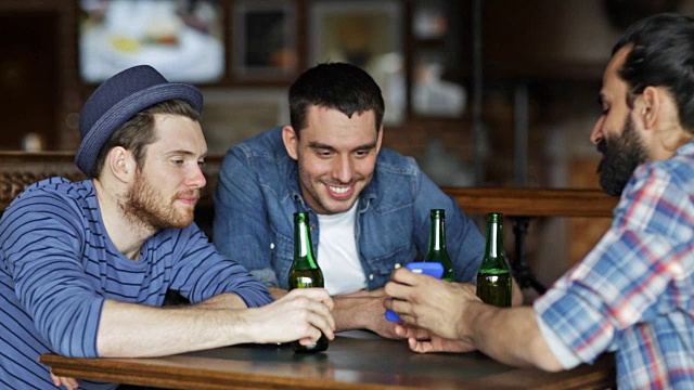 男性朋友拿着智能手机在酒吧或酒吧喝瓶装啤酒视频下载