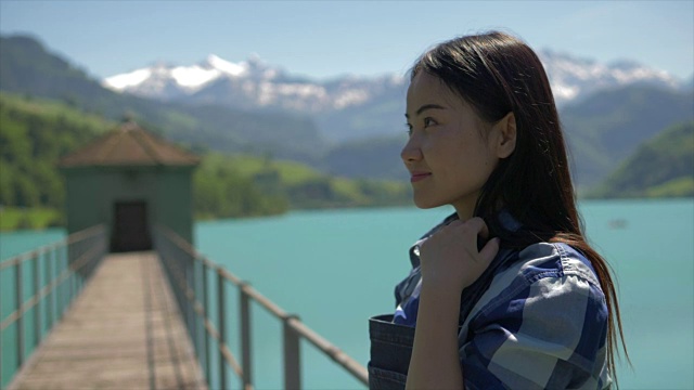 美丽和快乐的亚洲女孩享受她的一天在一个湖泊和山脉背景的高山景观步行桥视频素材