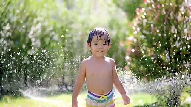 SLO MO亚洲婴儿玩水微笑和看镜头。视频下载