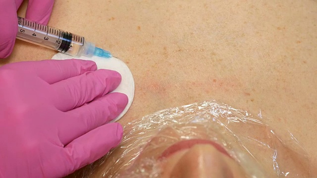英俊的女人有注射在颈部和胸部皮肤的程序使医生在粉红色的手套。中间疗法的概念视频素材