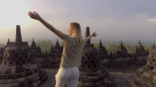 旅游女孩在婆罗浮屠寺拥抱日出的慢动作视频，印度尼西亚。People discovery Asia概念视频下载