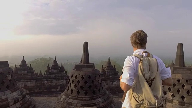 印尼婆罗浮屠寺，一名男子凝视日出的慢动作视频。人们旅行冒险的概念视频下载
