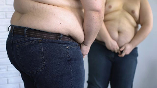 肥胖男性在镜子前用力穿牛仔裤，健康，不安全感视频素材